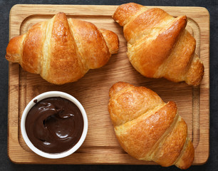 Croissants on a wooden board with chocolate paste. View from above.