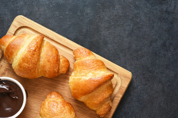 Croissants on a wooden board with chocolate paste. View from above.
