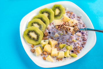 muesli with kiwi and apple with milk on a blue background