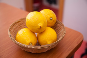 Lemons basket on a wooden table in a home kitchen background