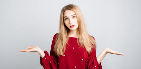 Beautiful girl with with long blonde hair feels doubt while makes choice, dressed in red casual...