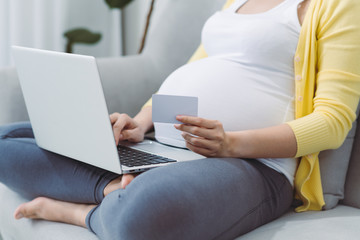 Naklejka premium Happy pregnant woman pays order with credit card in online store at home. Online shopping