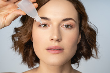 Fototapeta premium Beautiful Caucasian female treating her tired eyes