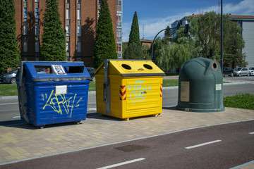 Contenedores de reciclaje de papel, plático y vidrio cerca del carril bici