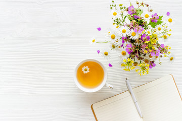 Wild flowers bouquet with cup tea on a table, top view