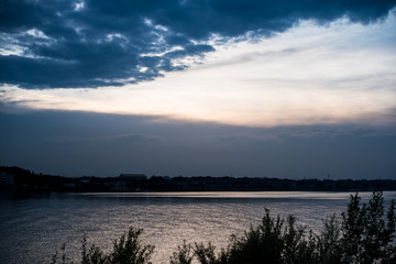 sunset over the river. the sky after the rain. clouds are reflected in the water. Summer evening in nature. River and reflection. Miserable summer