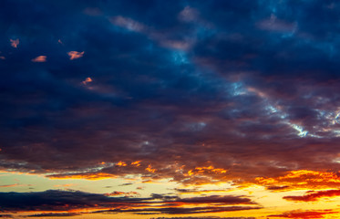 Panorama of the evening sky with dramatic orange, purple and dark blue clouds. Background image