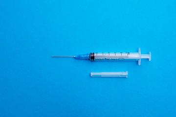 Medical syringe isolated on a blue background close-up. Minimalistic. The view from the top. Concepts of medicine. Antibiotics, painkillers, vitamins. Concept of different treatment methods