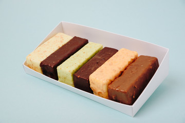 Set of cakes in icing and chocolate on a light background