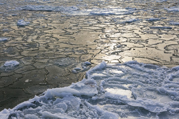 Natural sea ice blocks breaking up against the shore and ice during freezing winter weather. In the background