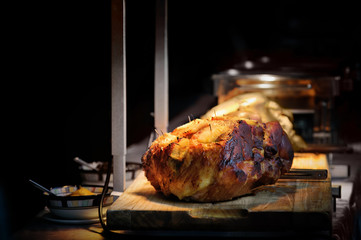 roasted ham pork with juicy pices pinapple slice in party dinner with hot lamp in dark background