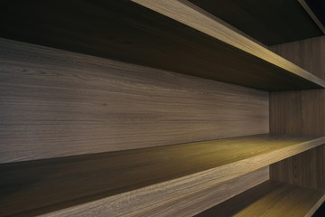 empty space of built in wooden shelf at wall with down-light