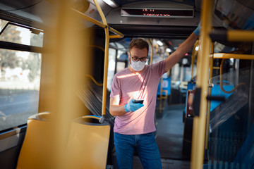 Man with medical protective mask and gloves standing in an emtpy bus.