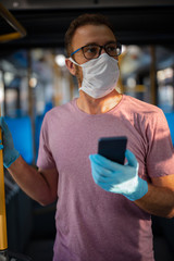 Man with medical protective mask and gloves standing in an emtpy bus.