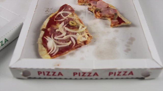 side slip of the hand of a pizza chef with blue gloves gently places an Italian pizza on the pizza box next to an empty one with crusts only