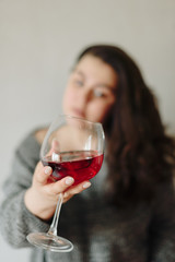 close-up of a girl in a grey sweater with a glass of red wine