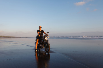 Man on a motorcycle on the beach during sunset