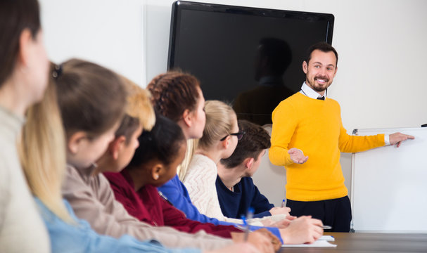 male and female students following explanations of mature teacher in class