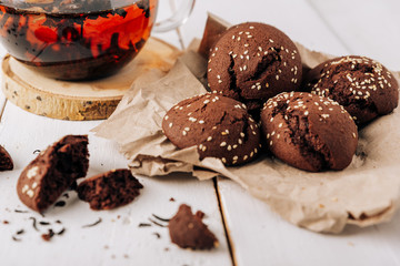 Teapot with black tea and homemade chocolate cookies on a white natural wooden background