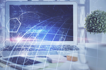 Double exposure of desktop with computer and world map hologram. International data network concept.