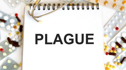 Plague-inscription on a notebook, next to a lot of multi-colored tablets, stethoscope. A medical concept.