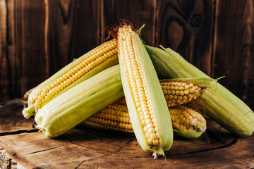 Fresh corn on the cob on a brown natural wood background close up