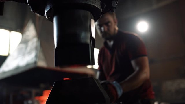 a blacksmith forges a red hot metal billet with a blacksmith's hammer
