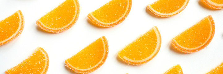 citrus jelly slices in sugar. marmalade slices of oranges isolated on a white background. repeating pattern, top view, flat lay. banner