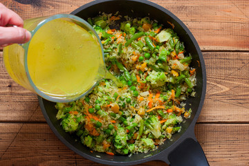 Cooking rice with frozen vegetables step by step, step 5 - adding broth, top view, horizontal