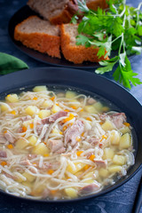 Homemade noodle soup with duck in black plate, selective focus