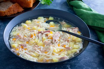 Homemade noodle soup with duck in black plate, selective focus