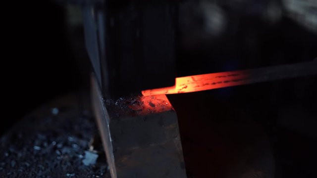 a blacksmith forges a red hot metal billet with a blacksmith's hammer
