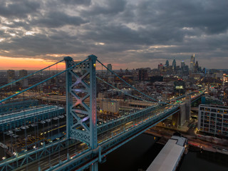 Philadelphia at night, aerial view of skyline at sunset with Benjamin Franklin Bridge and waterfront, skyscrapers dominating cityline against dramatic sky