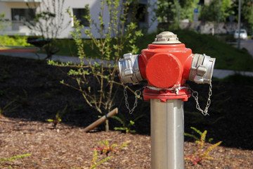 Painted steel hydrant stands on the lawn of a multistorey apartment. Fire hydrant at a public place. 