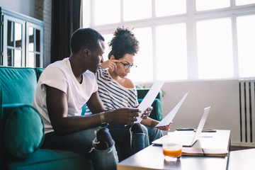 Concentrated couple sitting with documents at home