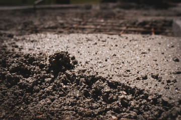 Close-up of wet cement solution poured on reinforcing metal bars on construction site, engineering concept