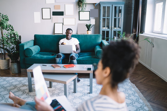 Tranquil couple browsing laptop and sitting on couch in living room
