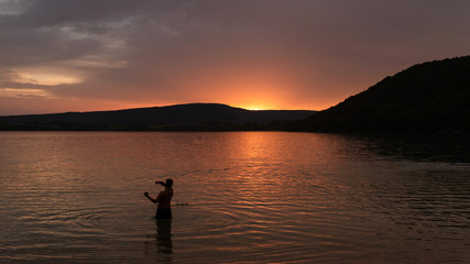 Fototapeta na wymiar Man throwing stones in the Chalain lake, France 