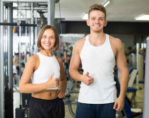 Portrait of cheerful young european couple standing together in gym indoors