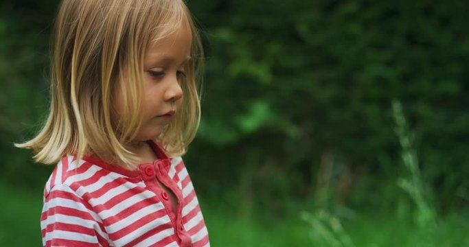 Little preschooler standing in garden in summer