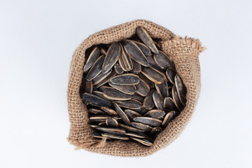 Burlap sack of sunflower seeds isolated on white background. Top view, closeup, copy space. Food, harvest, farming, agriculture concept