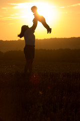 Silhouettes of mother and child in her arms on the background of sunset sky