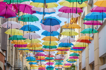 Fototapeta na wymiar Colorful umbrellas cover a shopping street in Carcassonne, Aude, Occitanie, France
