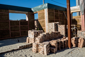 Construction site. Construction of walls made of bricks and straw.