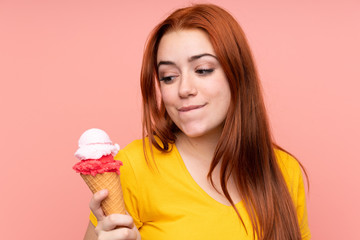 Redhead teenager girl with a cornet ice cream over isolated background