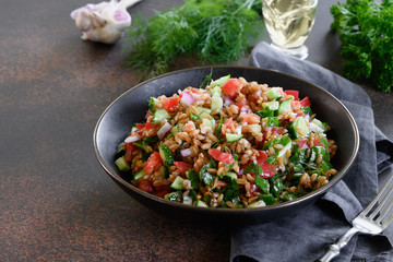 Whole Grain spelt salad with seasonal vegetables on dark background. Close up. Space for text.