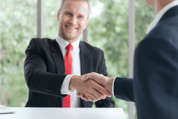 Young professional look Caucasian business man in formal suit shaking hand with partner or customer after finish an agreement or success a contract.