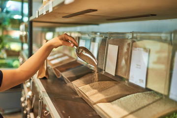 young woman with metal roll on the background of bulk cereals in the store, zero waste concept.