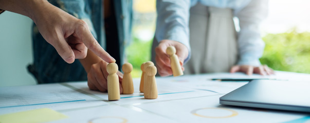 A group of business team brainstorming and planning strategy together with.wooden people in a...