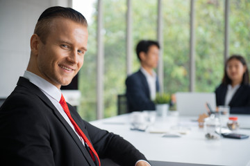 Portrait photo of handsome caucasian business man in formal suit uniform sitting in office meeting room.